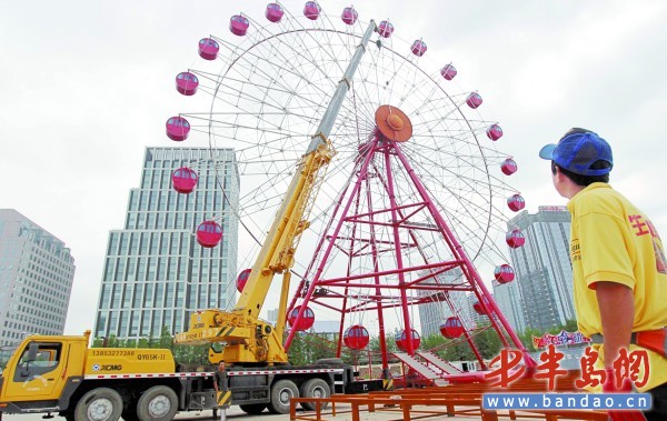 啤酒城內，工作人員正在進行摩天輪裝飾施工。